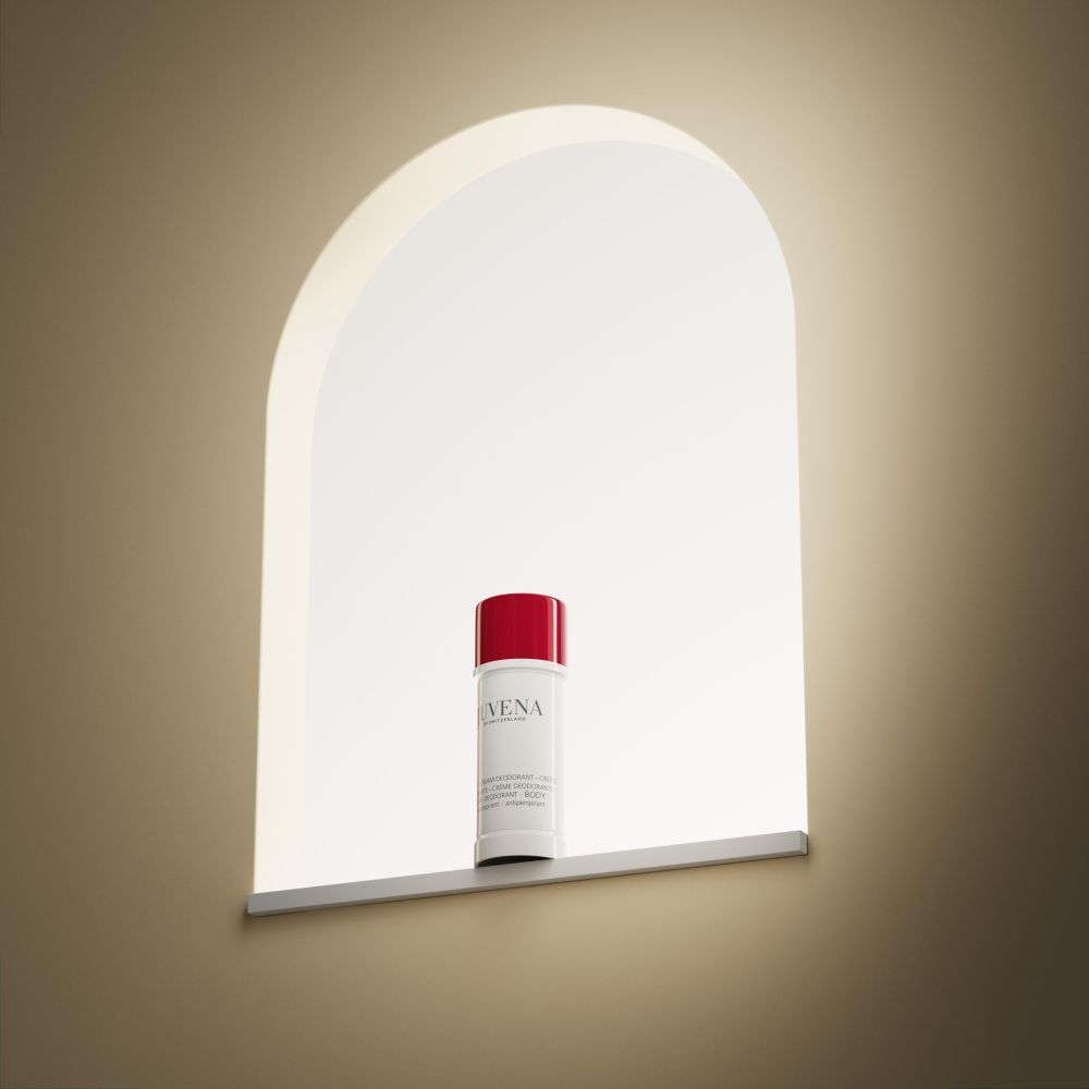 Stick de déodorant dans une niche. Bouchon rouge, corps blanc. Inscription : Juvena. Nom du produit illisible.