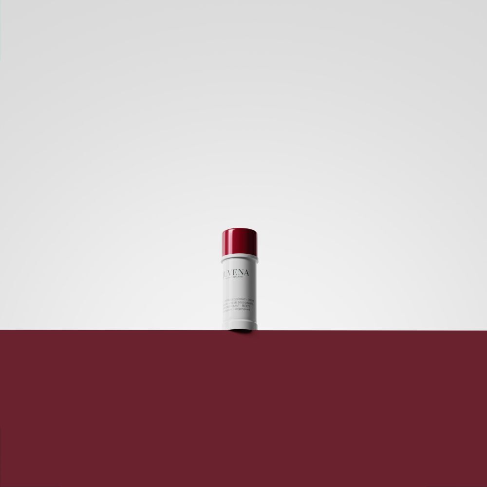 Stick de déodorant à bouchon rouge sur fond blanc et rouge. Nom du produit illisible.