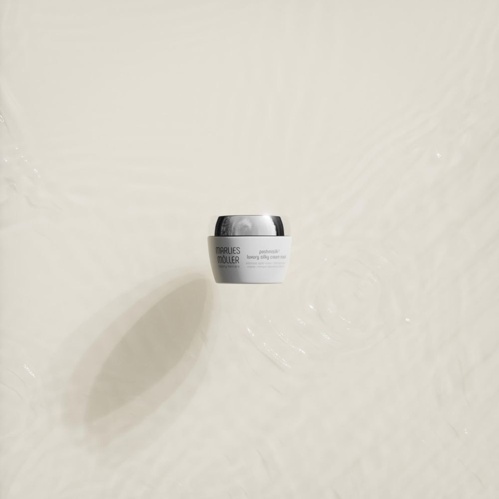 Pot blanc à couvercle argenté dans l'eau. Nom du produit: Marlies Möller Pashmisilk Luxury Silky Cream Mask.