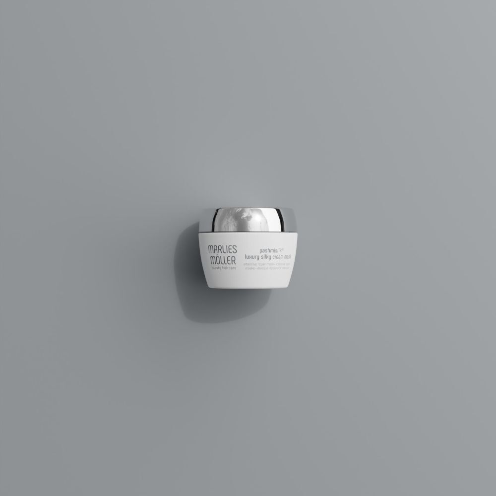 Pot blanc à couvercle argenté sur fond gris. Nom du produit: Marlies Möller Pashmisilk.