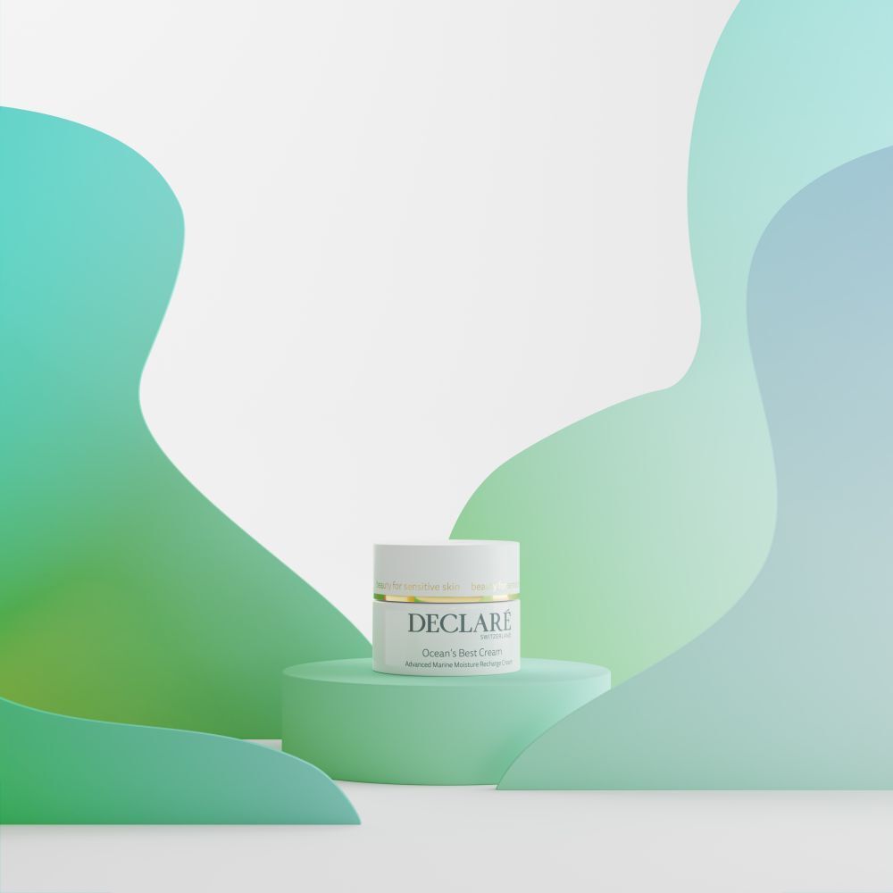 Pot blanc sur socle vert. DECLARÉ Ocean's Best Cream. Fond: formes vertes et bleues.