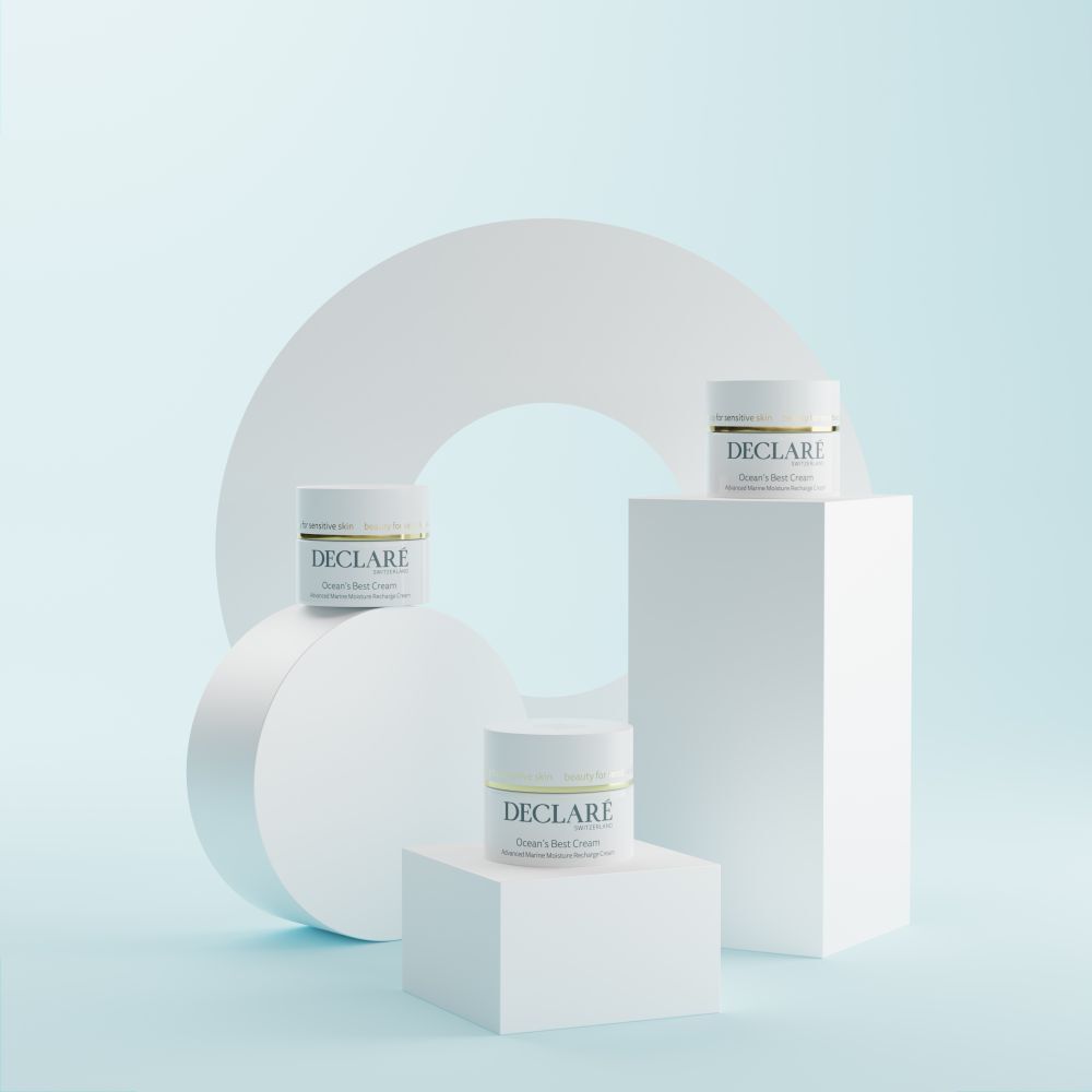 Trois pots blancs sur socles. DECLARÉ Ocean's Best Cream. Fond: formes géométriques blanches.