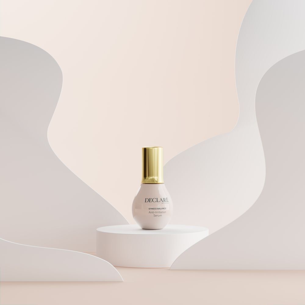 Flacon de sérum rose sur socle blanc. Bouchon doré. Formes blanches décoratives en arrière-plan.