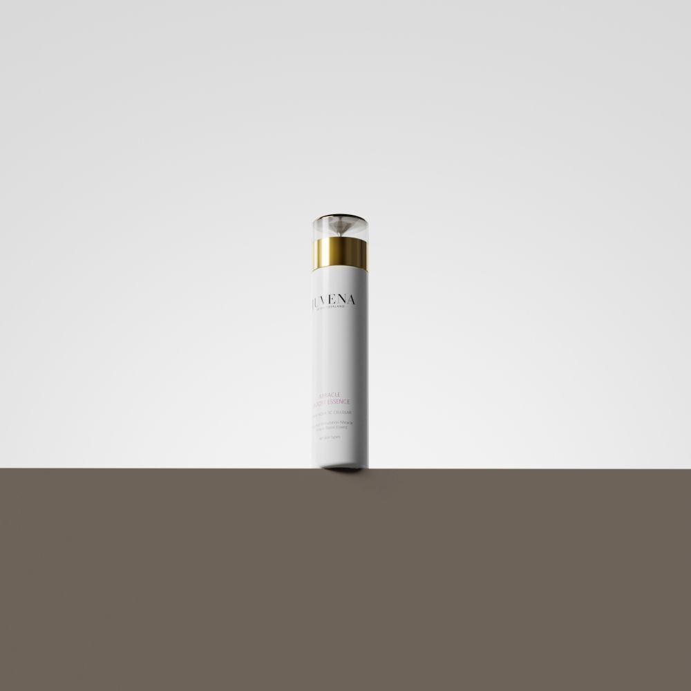 Flacon blanc avec bouchon doré. Juvena Miracle Boost Essence. Sur fond marron.