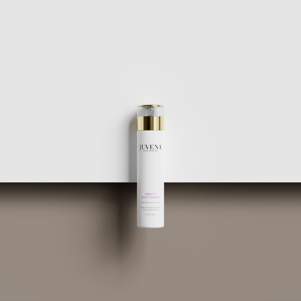 Flacon blanc avec bouchon doré. Juvena Miracle Boost Essence. Sur fond blanc.