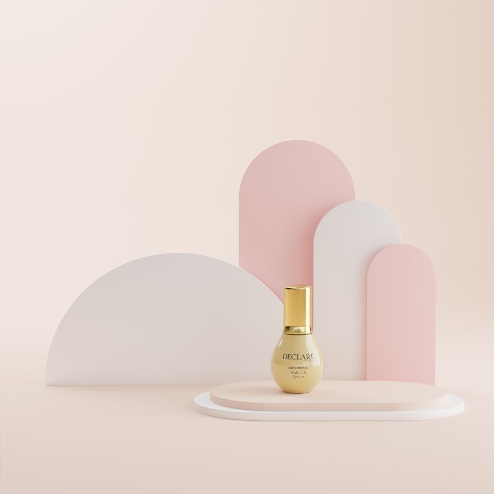 Flacon de sérum sur socle. Fond avec formes roses et blanches. DECLARÉ, AGE CONTROL, Multi Lift Serum.