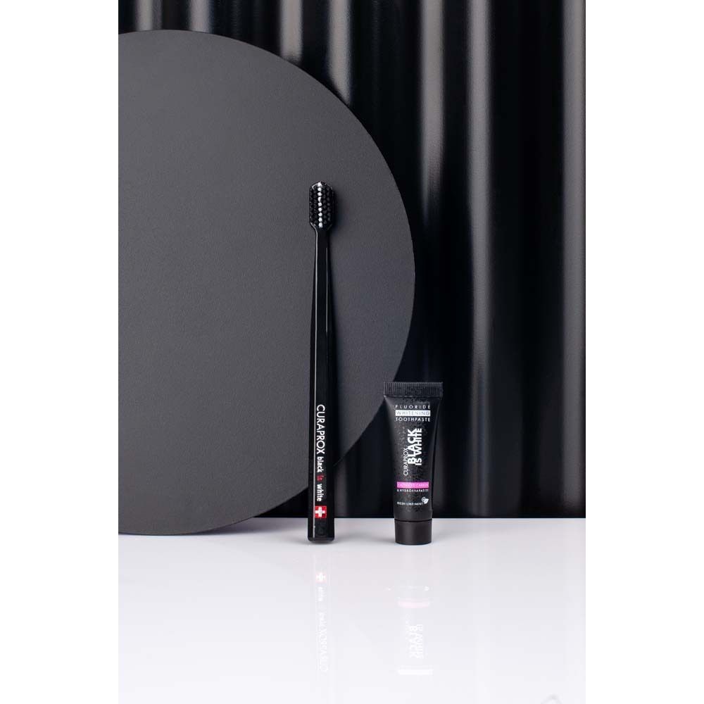 Pack CURAPROX Black is White. Brosse à dents et dentifrice noirs. Fond avec cercles. Marque visible.