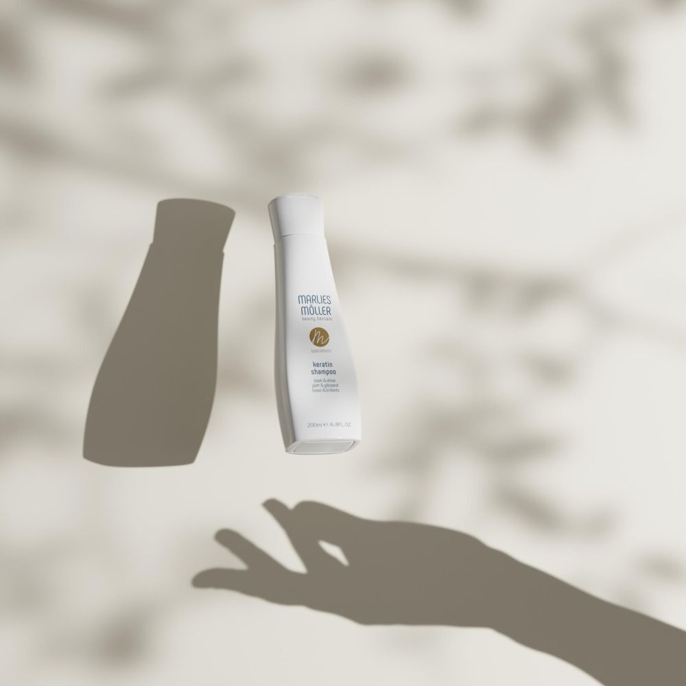 Bouteille de shampooing Marlies Möller Kératine flottant devant un fond avec des ombres.