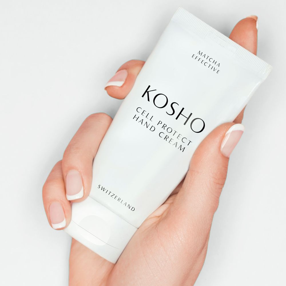 Main tenant un tube blanc KOSHO Cell Protect Hand Cream. Texte: Matcha Effective, Switzerland.