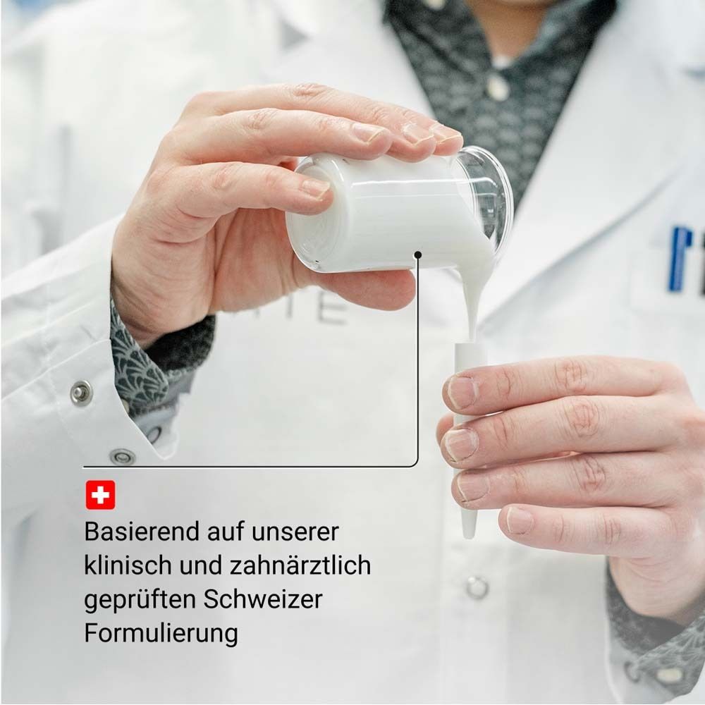 Personne verse du liquide dans un tube à essai. Texte: Basé sur notre formulation suisse testée cliniquement et par des dentistes.