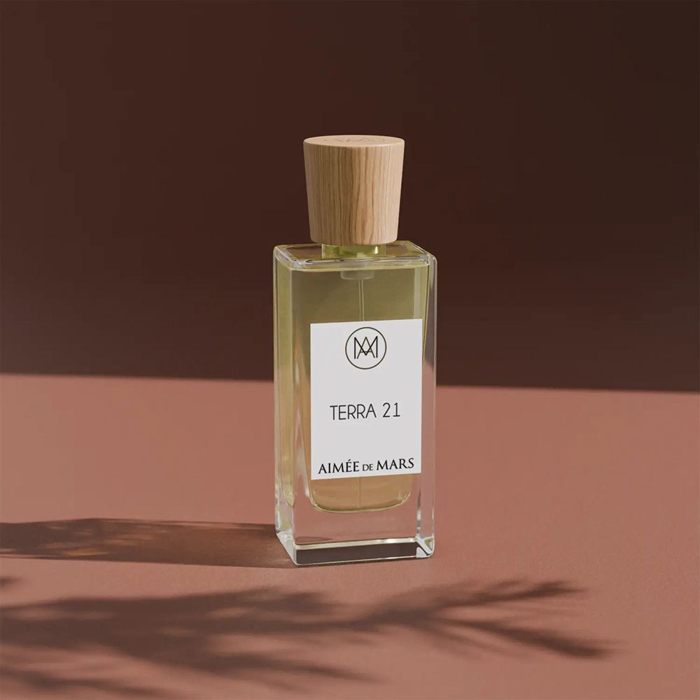 Flacon en verre avec bouchon en bois. Étiquette avec texte: Terra 21, Aimée de Mars. Fond rose.