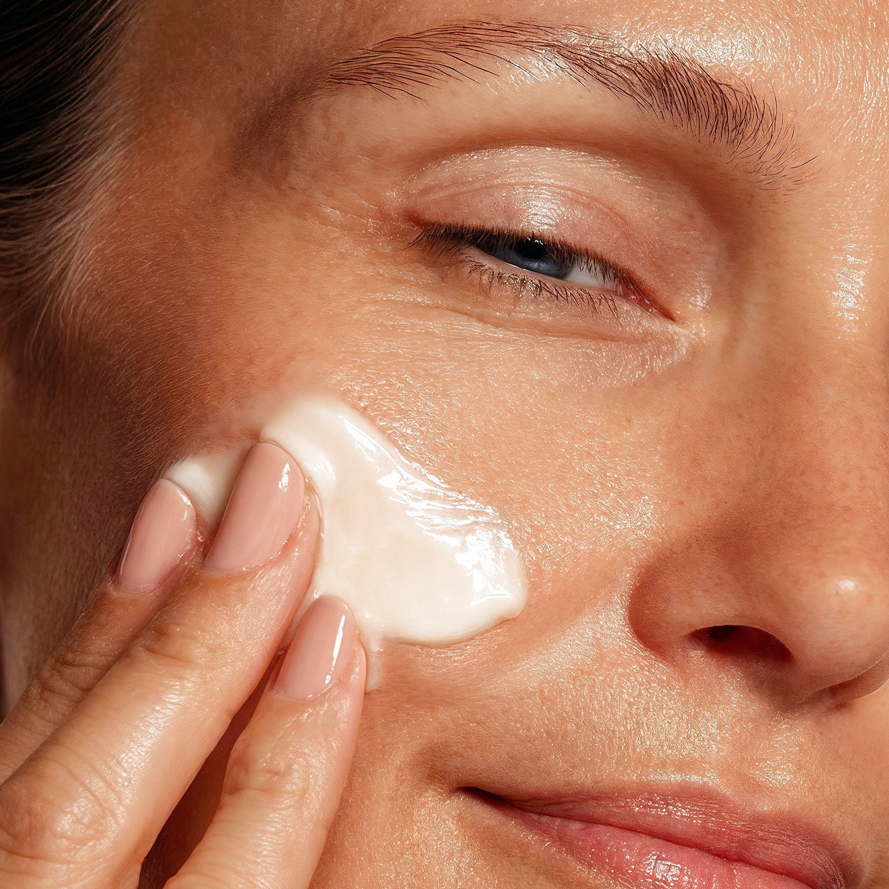 Gros plan d'une femme appliquant de la crème sur son visage. Soin de la peau.