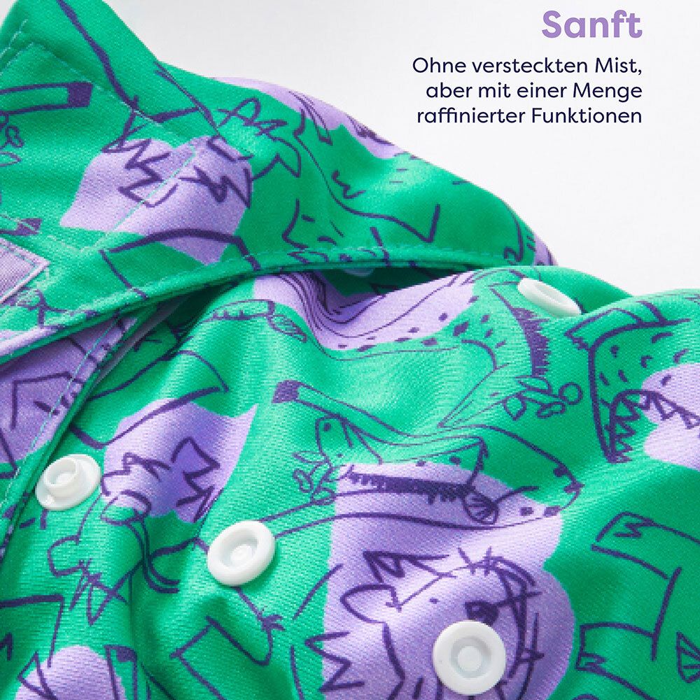 Gros plan d'une couche à motifs crocodiles. Texte : Doux. Sans substances cachées, mais avec fonctions.