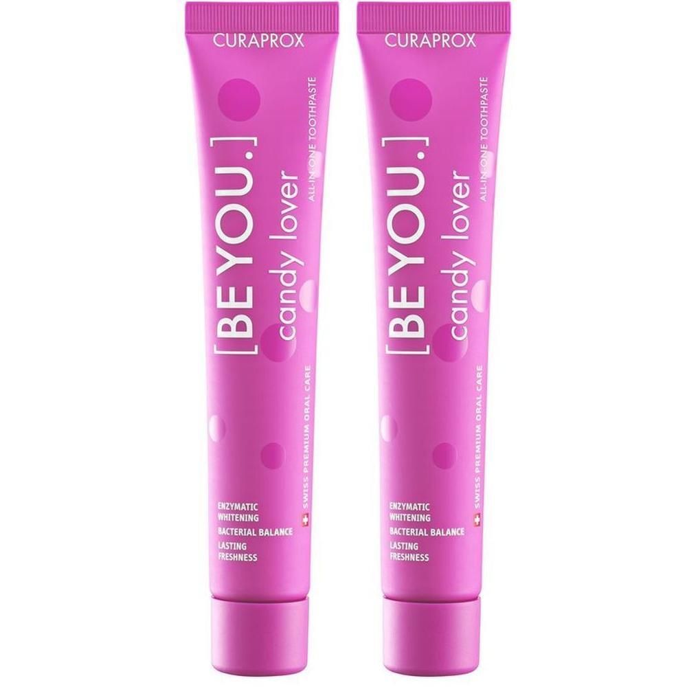 Deux tubes de dentifrice roses. Chaque tube porte l'inscription "[BE YOU.] candy lover" et "CURAPROX".