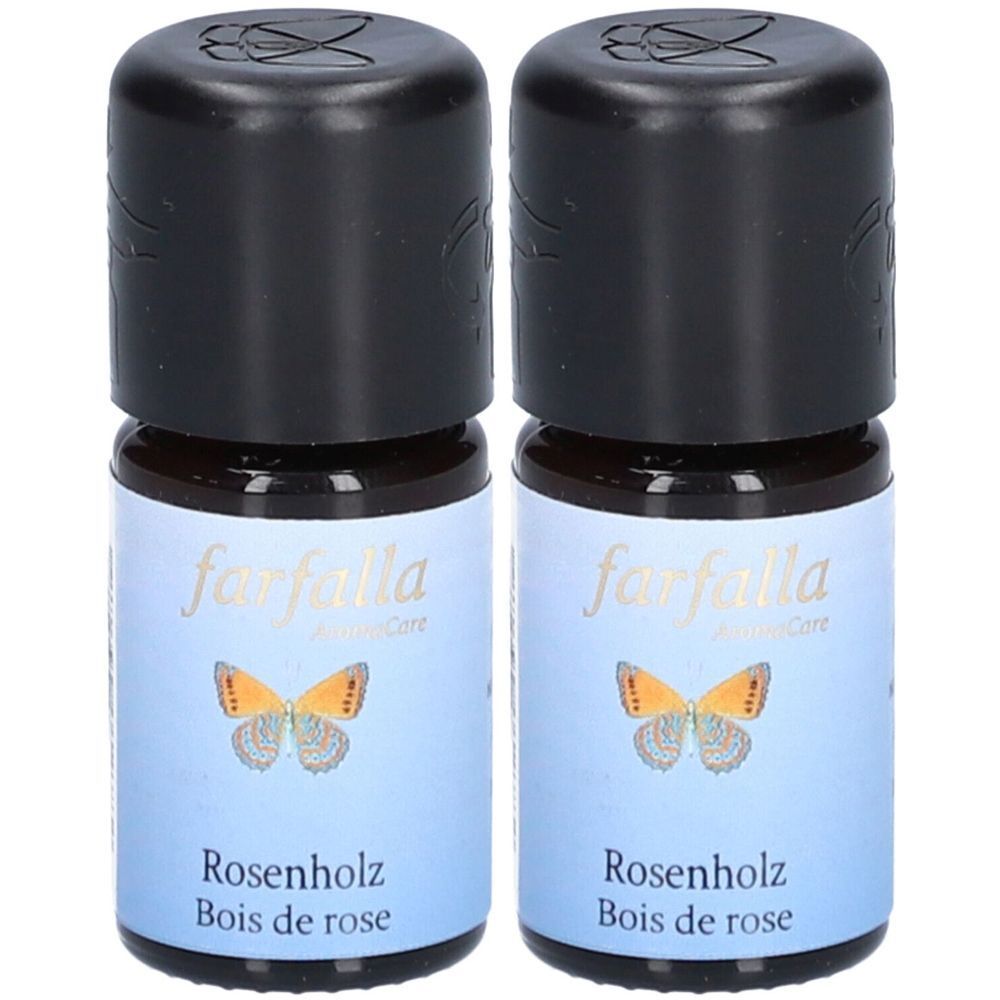 Deux flacons d'huile essentielle. Étiquettes bleues avec papillon et texte: Rosenholz, Bois de rose. Bouchons noirs.