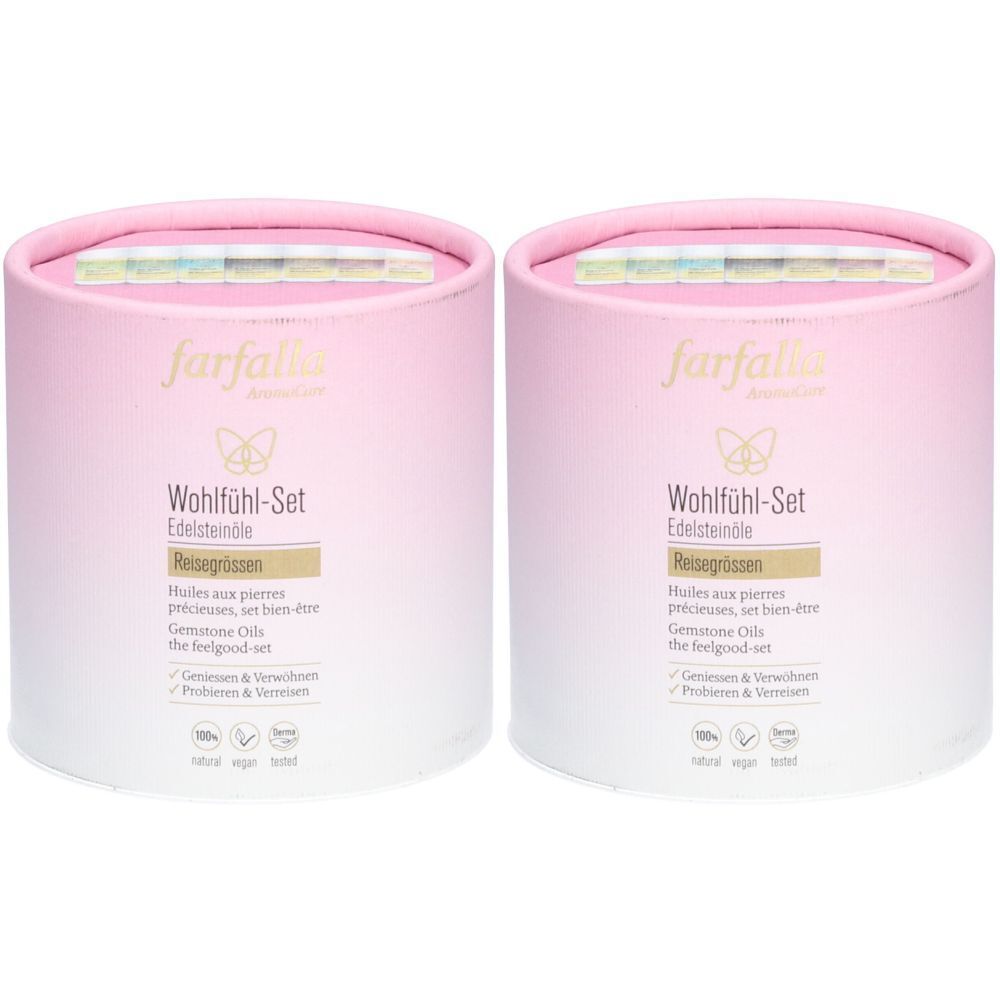 Deux coffrets cadeaux cylindriques rose et blanc. Inscription : farfalla, Wohlfühl-Set, Edelsteinöle. Avec des bandes colorées sur le dessus.