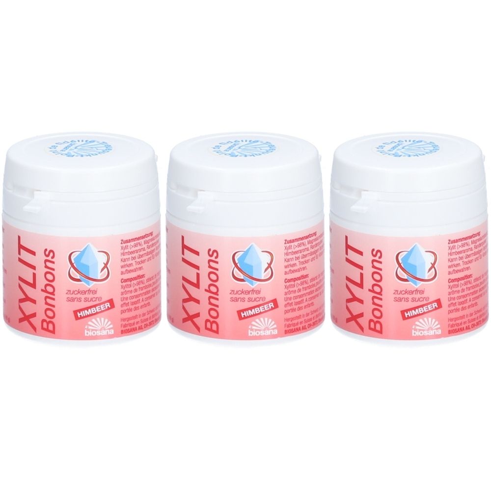 Trois pots de bonbons Xylitol framboise. Couvercles blancs, étiquette rose avec nom et logo du produit. Marque Biosana.