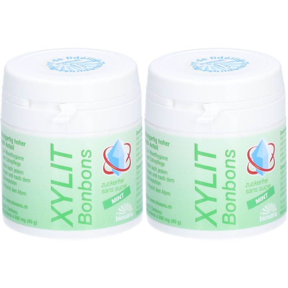 Deux boîtes blanches avec étiquette verte. Inscription: XYLIT Bonbons, Mint. Logo: cristal bleu.