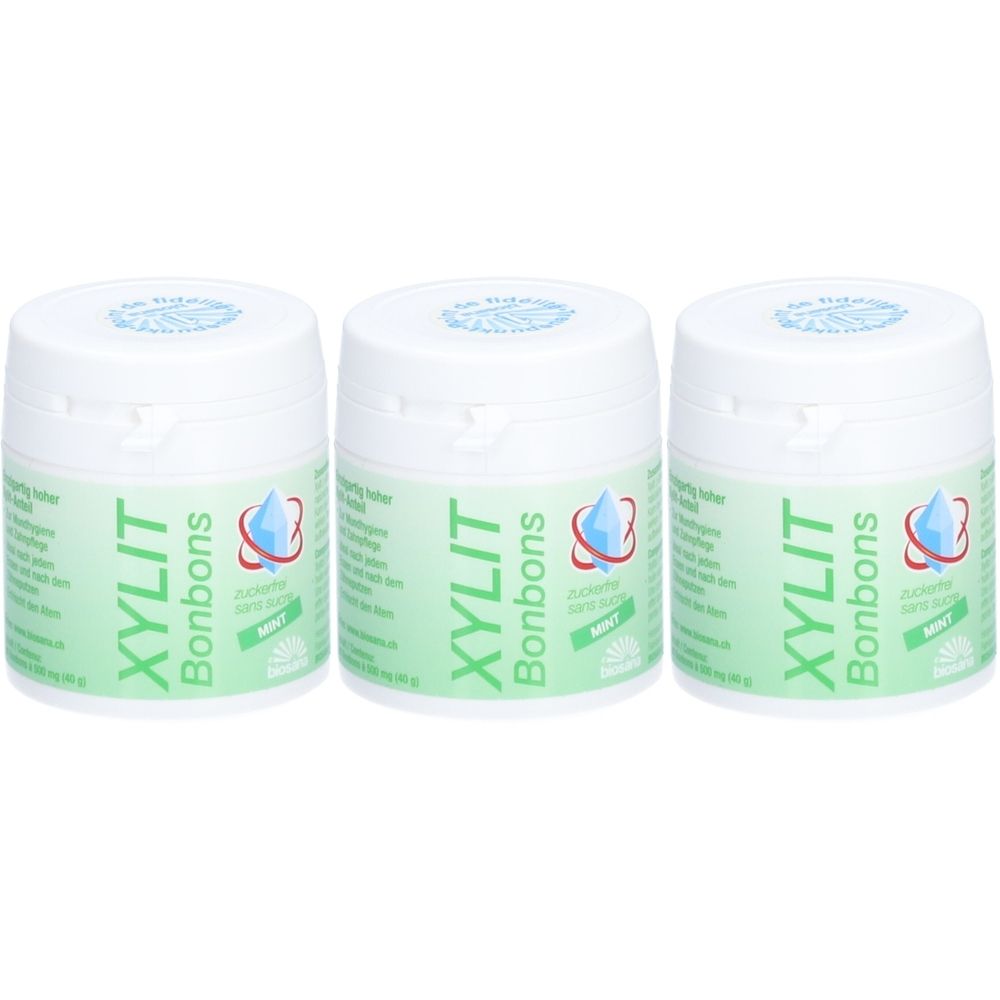 Trois boîtes blanches avec étiquette verte. Inscription : XYLIT Bonbons, logo goutte. Couvercles avec logo bleu.