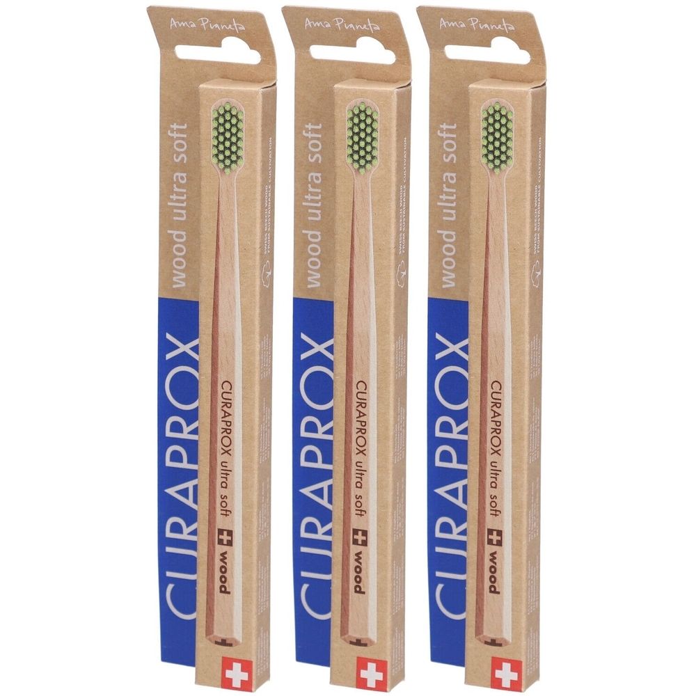 Trois brosses à dents emballées. Manche en bois, poils verts. Emballage bleu et marron avec logo CURAPROX et croix suisse.