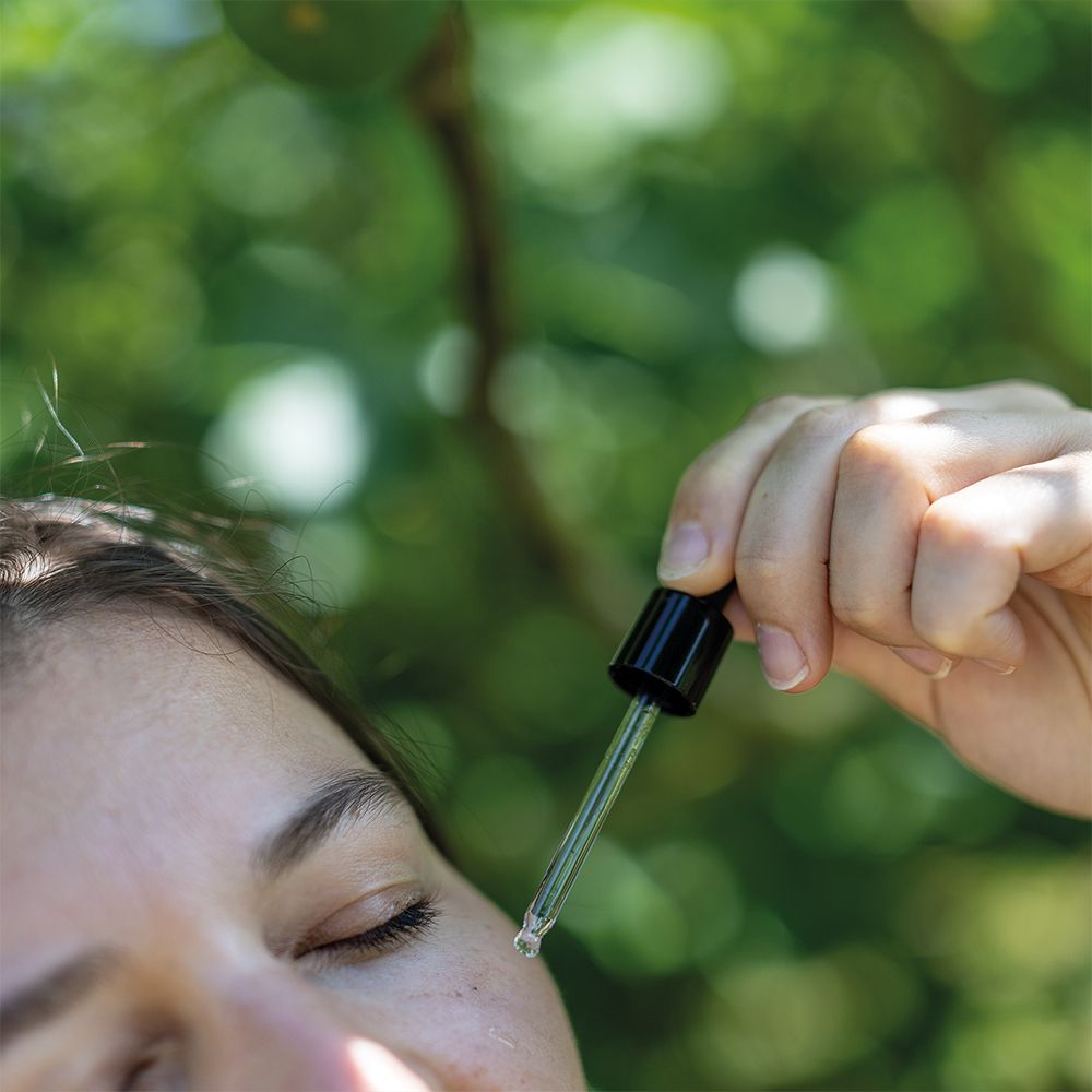 Gros plan sur un visage. Pipette dépose du sérum sur la peau.