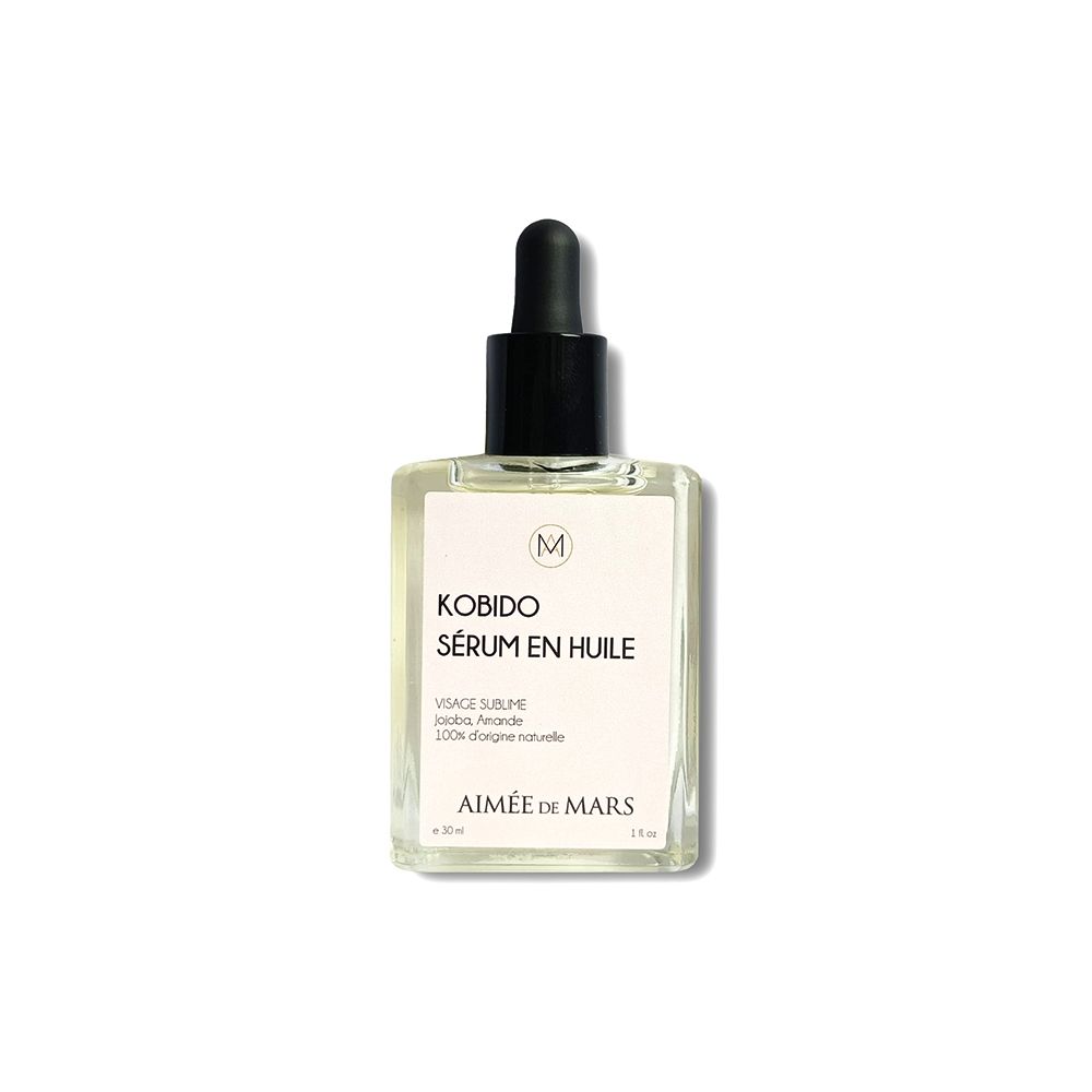 Sérum huileux clair en flacon carré avec compte-gouttes noir. Étiquette avec nom du produit et logo.