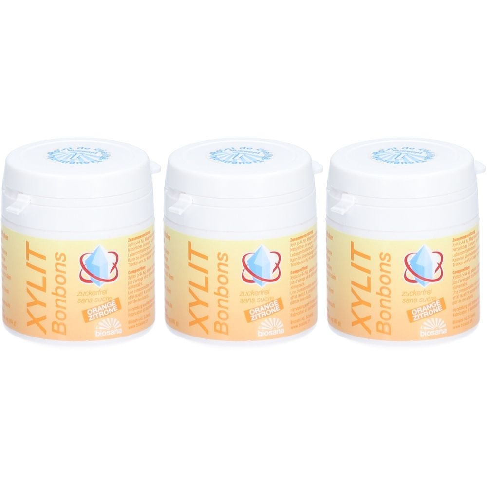 Trois boîtes blanches avec couvercles. Chaque boîte porte l'inscription "XYLIT Bonbons" et un logo. Autocollant "Orange Zitrone".