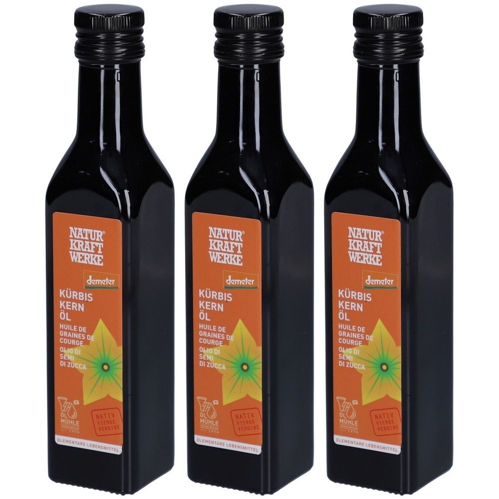 Trois bouteilles d'huile de graines de courge. Bouteilles noires avec étiquette. Inscription : NATUR KRAFT WERKE, KÜRBIS KERN ÖL, label Demeter.