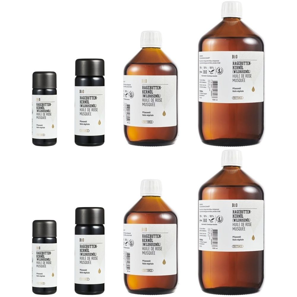 Plusieurs bouteilles et petits contenants étiquetés. Inscription : BIO HAGEBUTTEN KERNÖL. Bouteilles en verre brun, bouchons blancs et noirs.