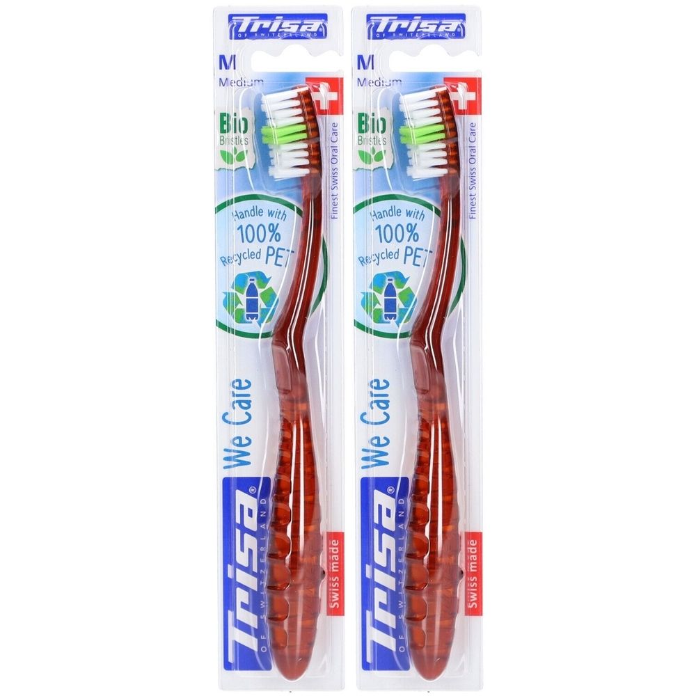 Deux brosses à dents emballées. Manche rouge, poils blancs avec accents verts. Marque Trisa, Medium.