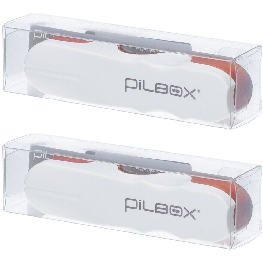 Deux coupe-comprimés dans des boîtes en plastique transparentes. Boîtier blanc avec insert rouge et inscription PILBOX.