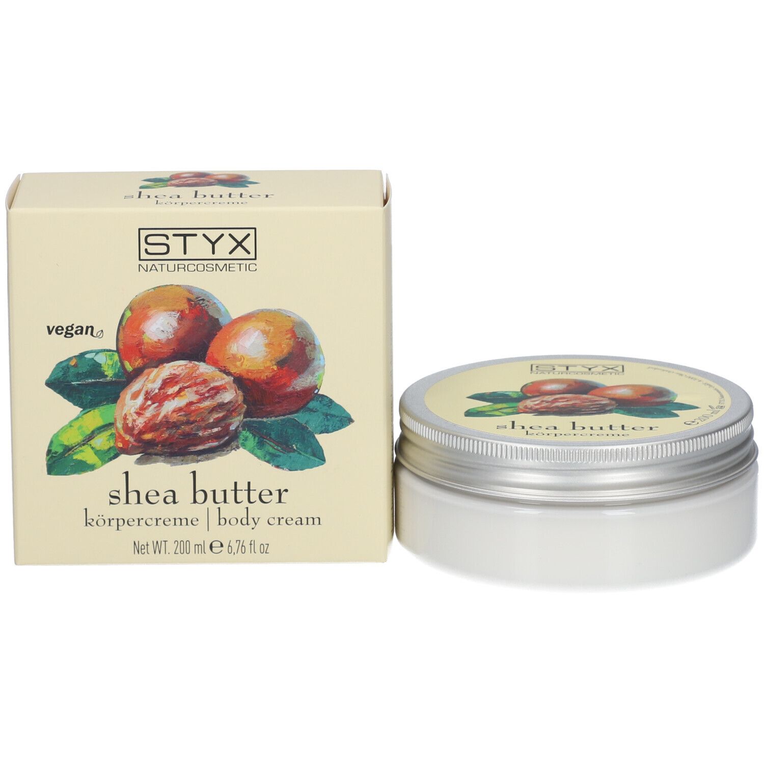 Pot de crème et carton. Sur le pot et le carton : STYX, crème corporelle au beurre de karité. Carton avec illustration de noix de karité et de feuilles.