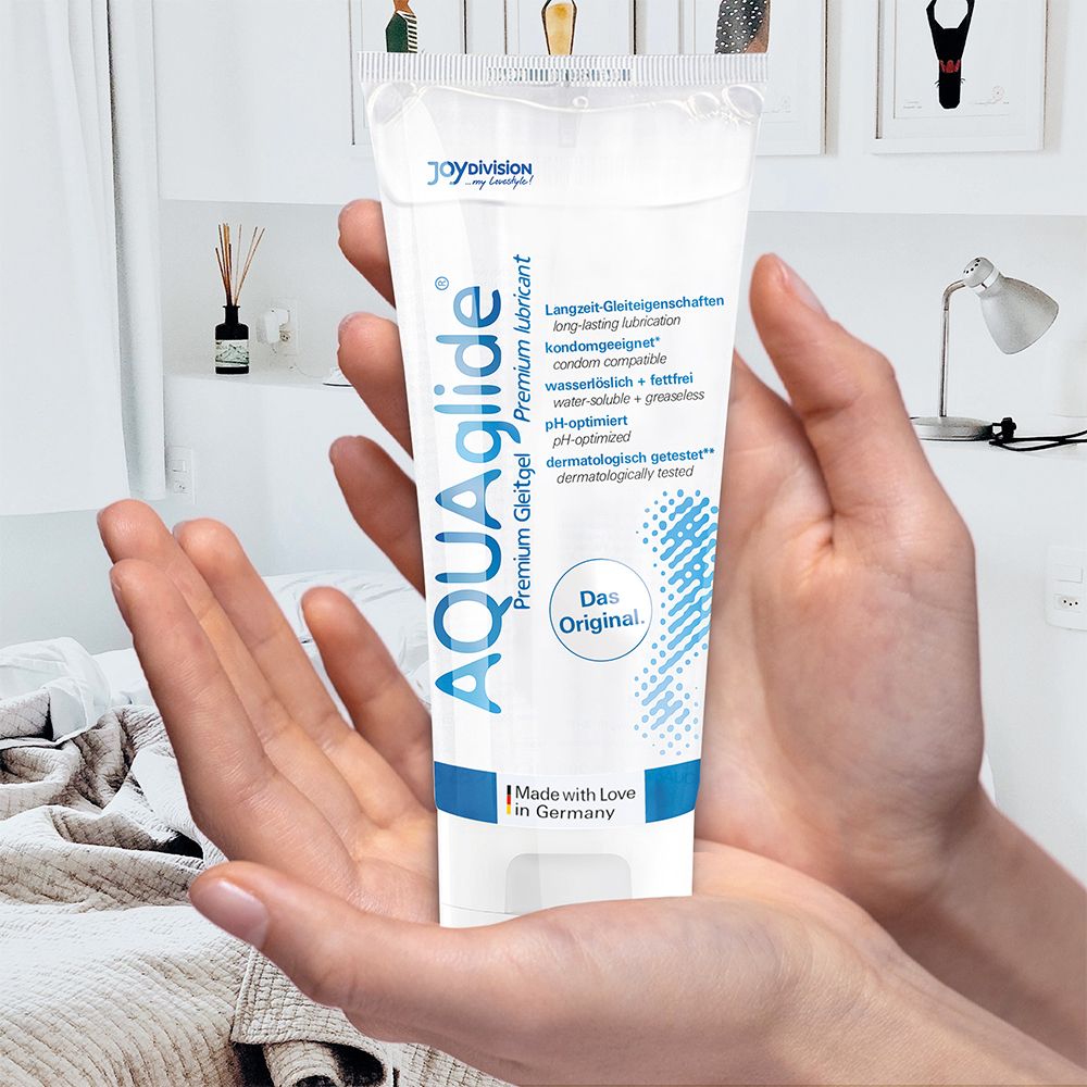 Mains tenant un tube de gel lubrifiant AQUAGLIDE Premium dans une chambre.