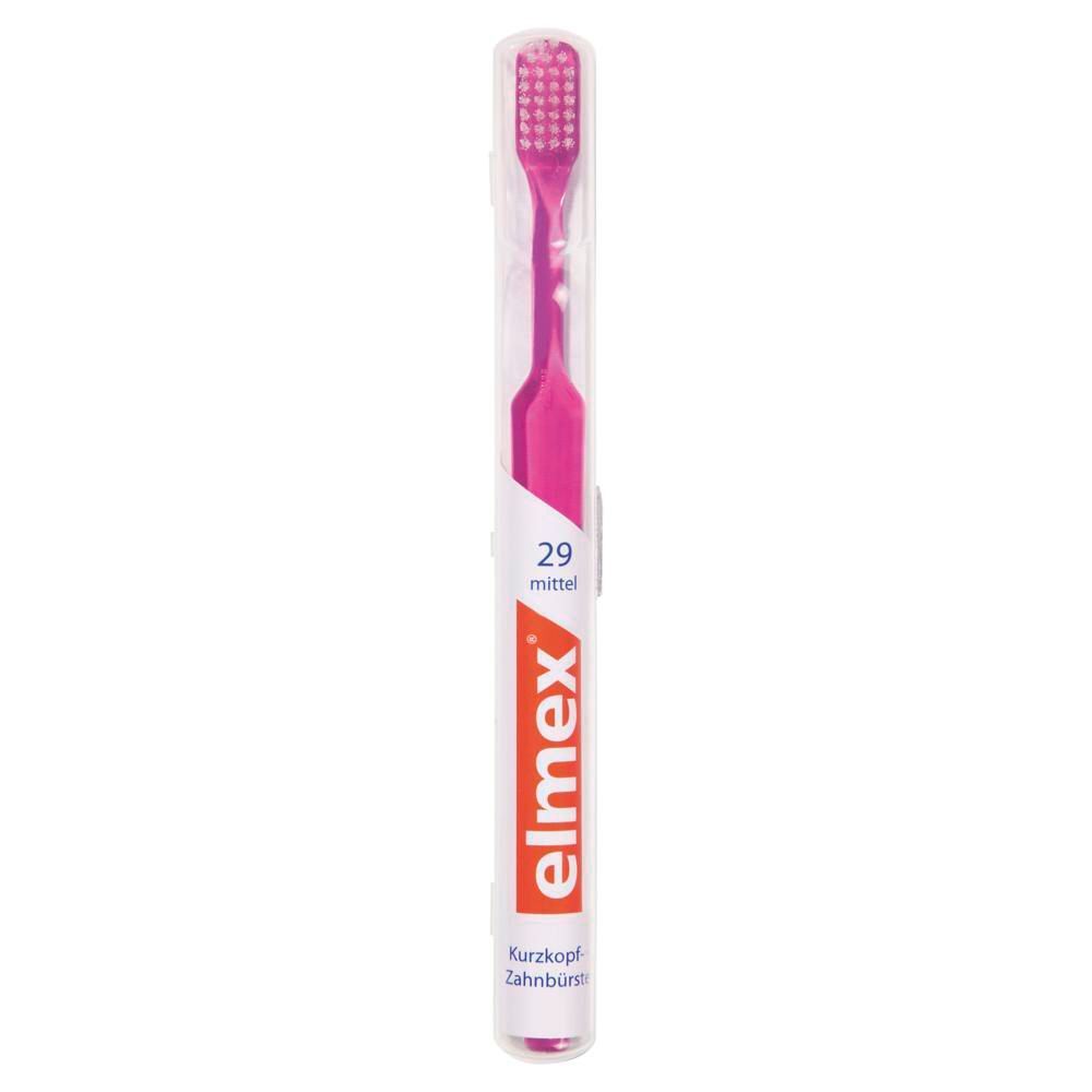 Brosse à dents rose dans emballage transparent. Poignée rose, soies moyennes. Marque elmex, texte: 29 moyen, tête courte.