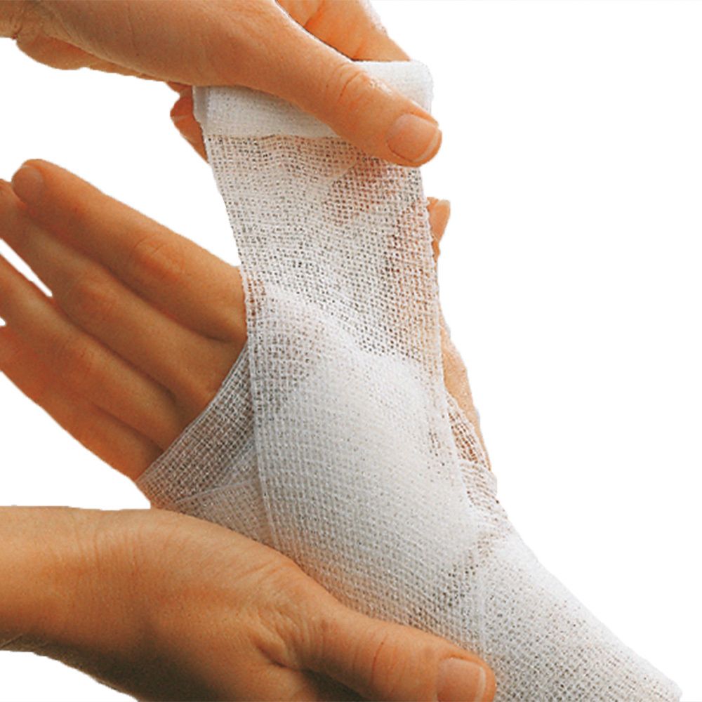 Un bandage blanc est enroulé autour d'une main. La main est tenue par deux mains.