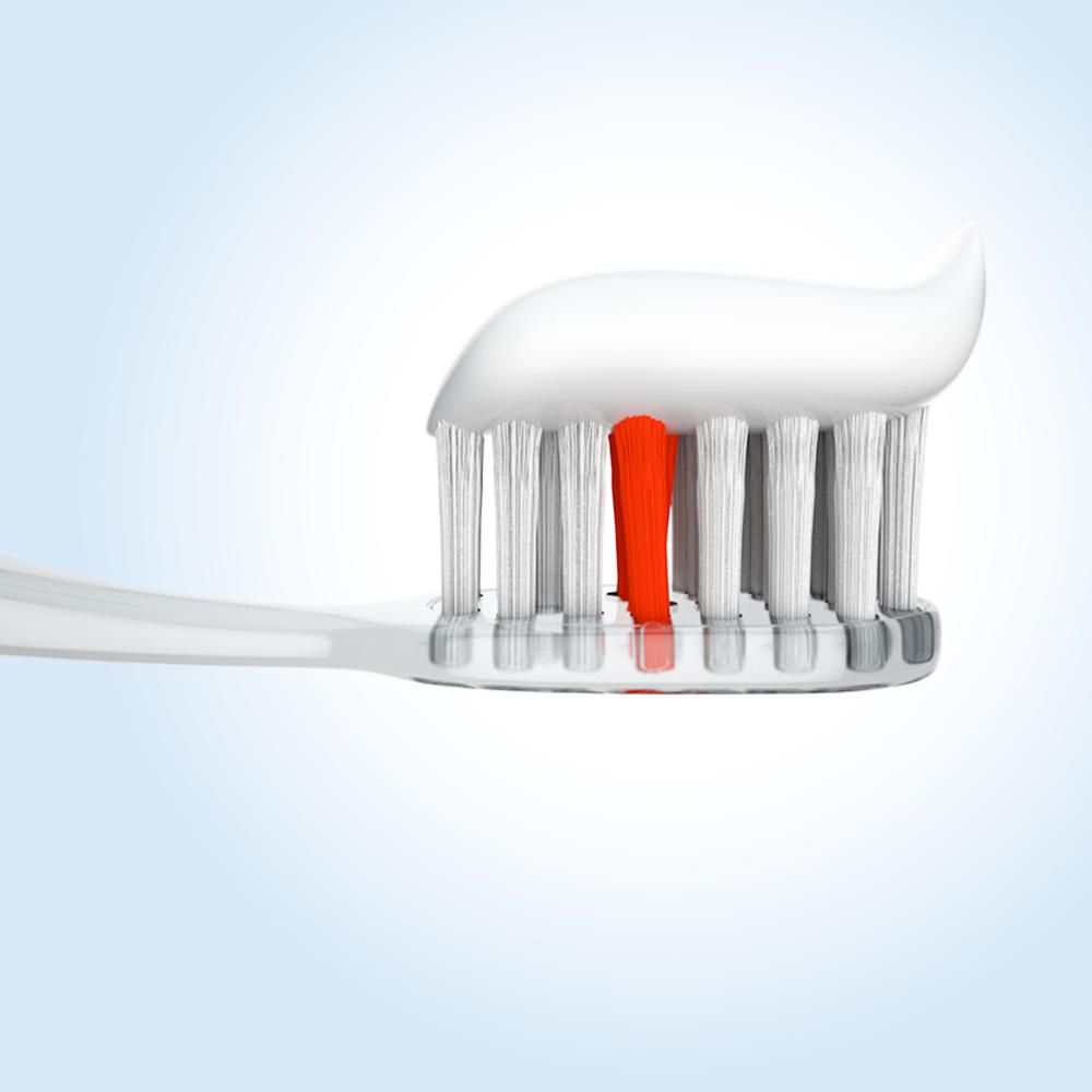 Brosse à dents avec dentifrice. Dentifrice blanc avec une bande rouge sur les poils blancs.