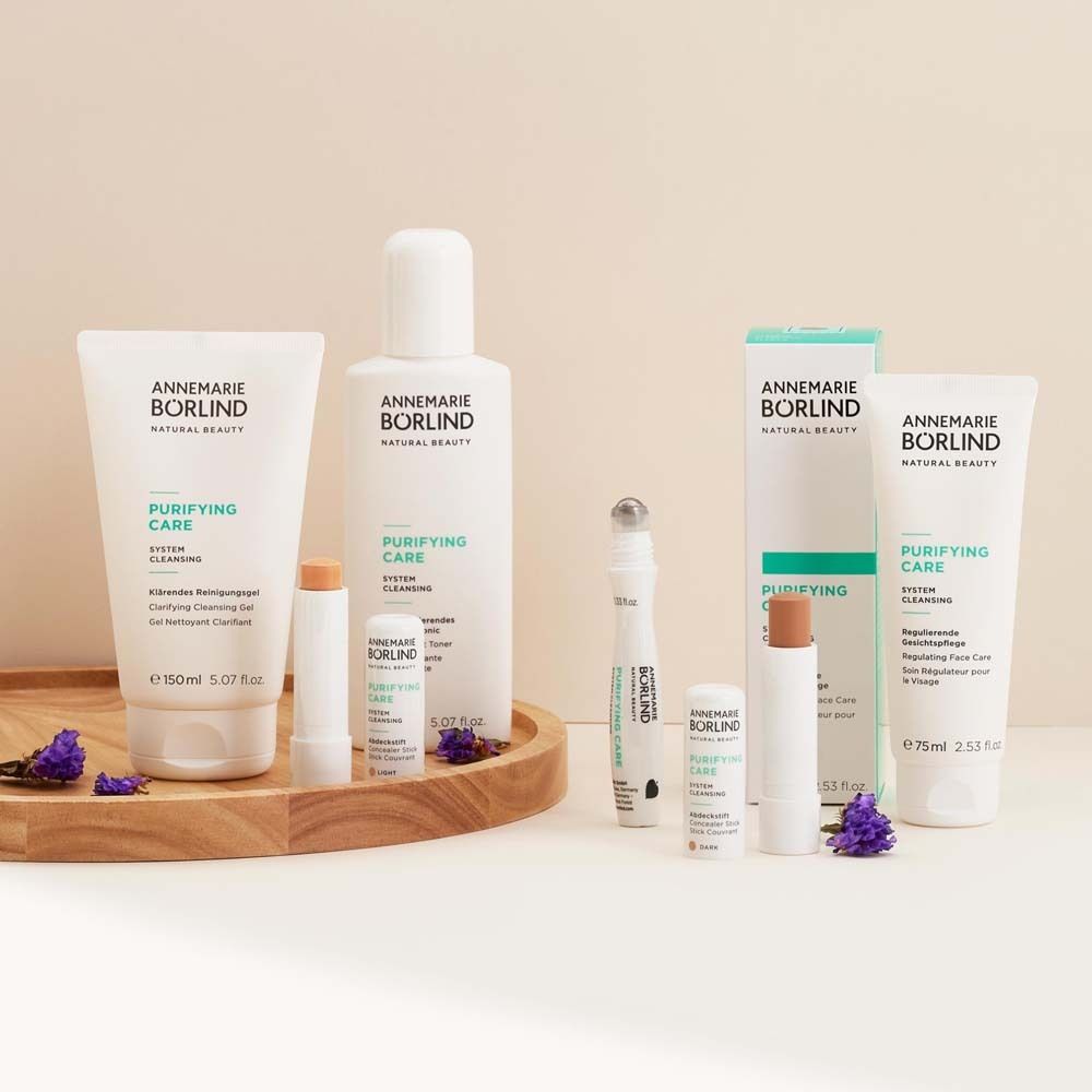 Divers produits cosmétiques sur plateau en bois. Produits ANNEMARIE BÖRLIND, PURIFYING CARE. Brins de lavande.