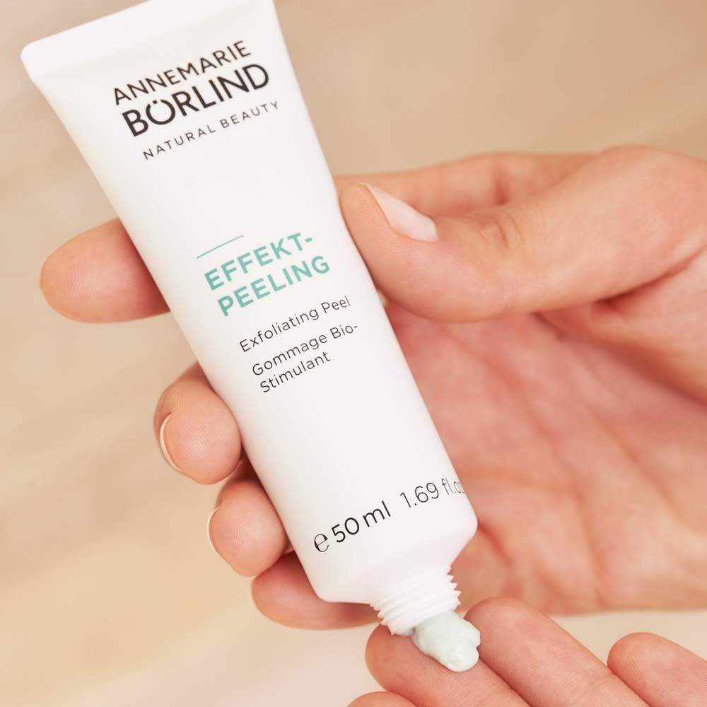 Main pressant EFFEKT-PEELING d'un tube blanc. Texture peeling verte sur doigt.