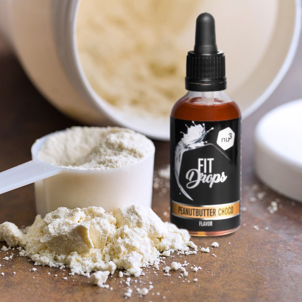 Bouteille de liquide brun avec compte-gouttes à côté d'une cuillère doseuse et de poudre de protéine. Inscription: FIT Drops Peanutbutter Choco Flavor.
