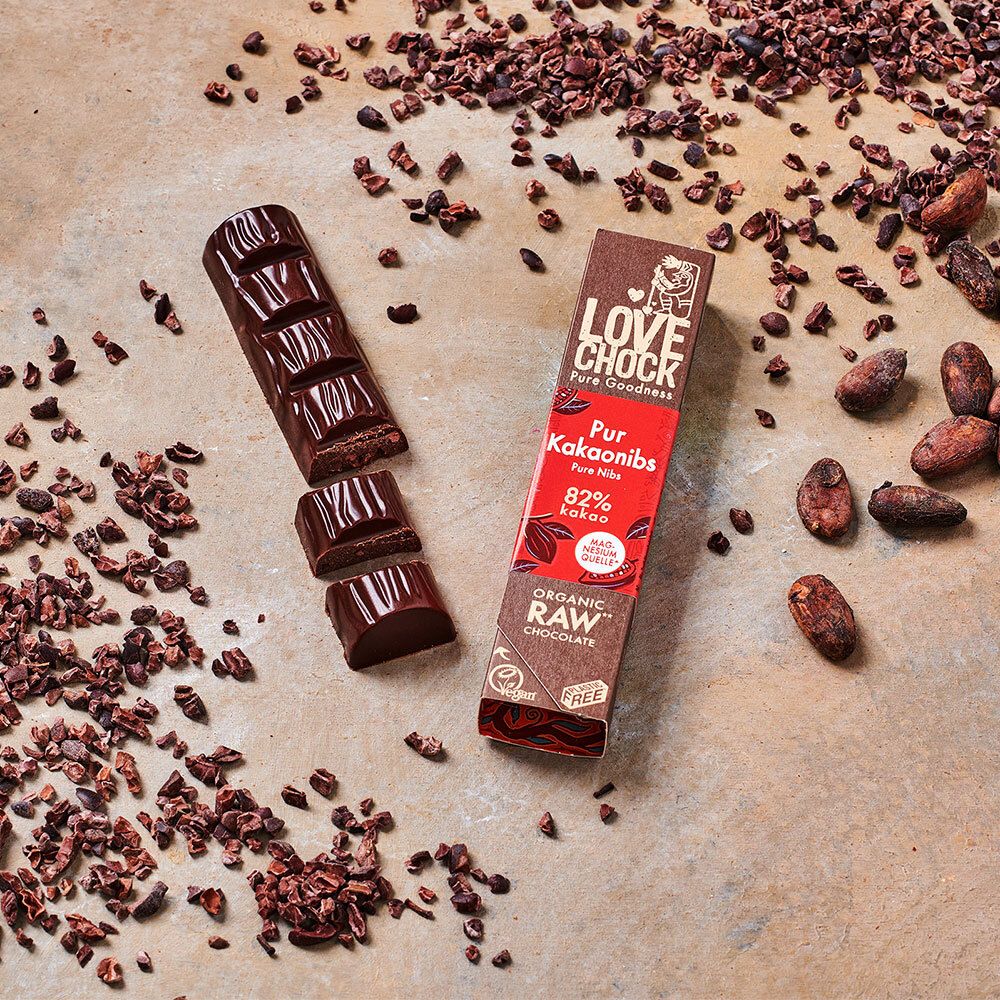Barre et morceaux LOVECHOCK Pur Kakaonibs 82% Kakao. Fèves et éclats de cacao dispersés. Emballage rouge. Vegan, certification bio.