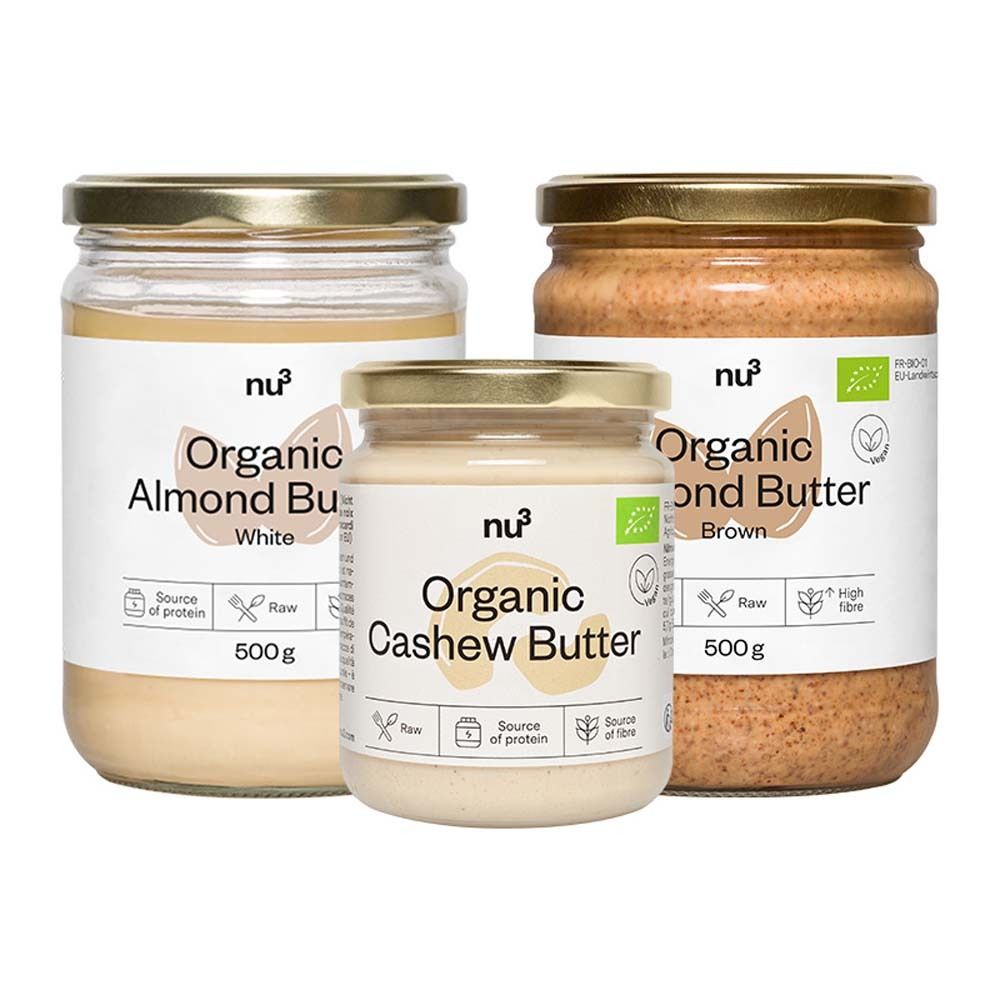 Trois pots de beurre de noix, étiquetés. Inscriptions : nu3 Organic Almond Butter White, Organic Cashew Butter, Organic Almond Butter Brown. Label bio.