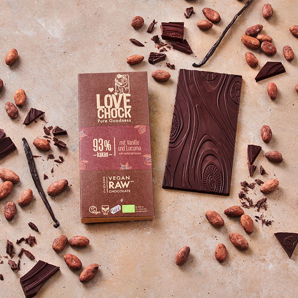 Tablette de chocolat LOVECHOCK et tablette cassée. Fèves de cacao et gousses de vanille. Inscription : 93% cacao, vanille et lucuma.