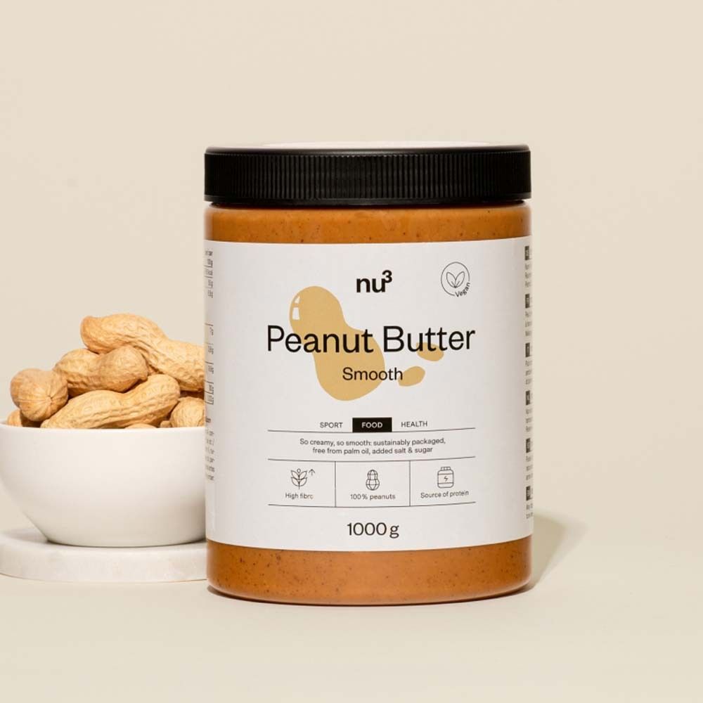 Un pot de beurre de cacahuète nu3 smooth. À côté, un bol de cacahuètes. Couvercle noir, étiquette blanche.