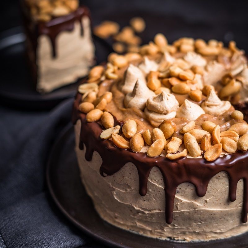 Gros plan d'un gâteau avec crème au beurre de cacahuète, cacahuètes et glaçage au chocolat.