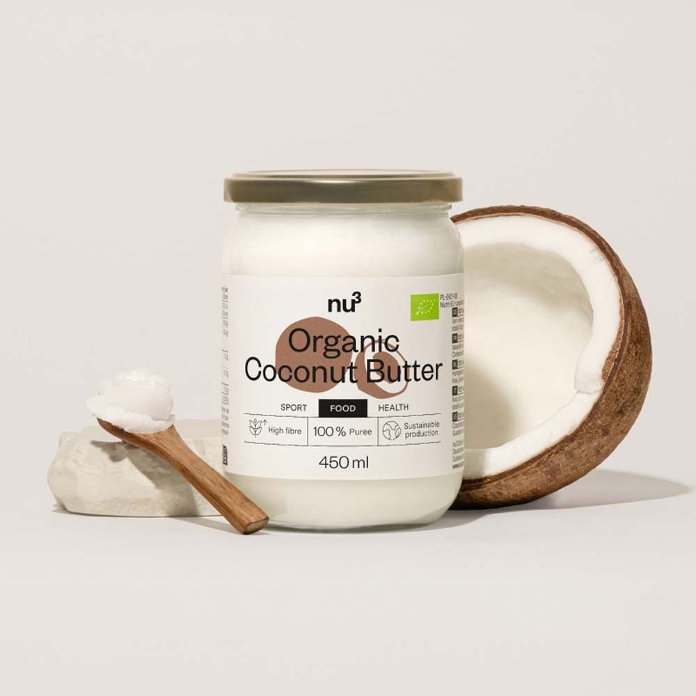 Pot de beurre de coco bio, à côté une moitié de noix de coco et une cuillère. Inscription : Organic Coconut Butter, 450ml.