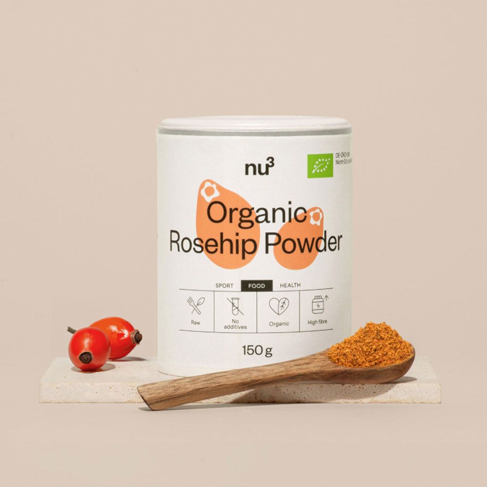 Une boîte de poudre de cynorrhodon nu3, à côté une cuillère en bois avec de la poudre et des cynorrhodons. Inscription : Organic Rosehip Powder, 150g. Label bio.