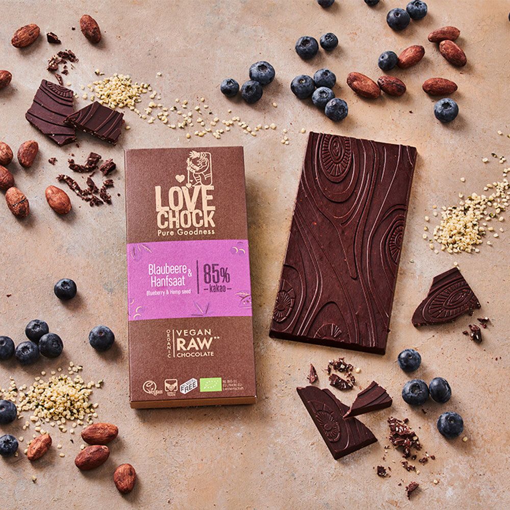 Tablette et morceaux de chocolat avec myrtilles et fèves de cacao. Emballage avec inscription Blaubeere & Hanfsaat.