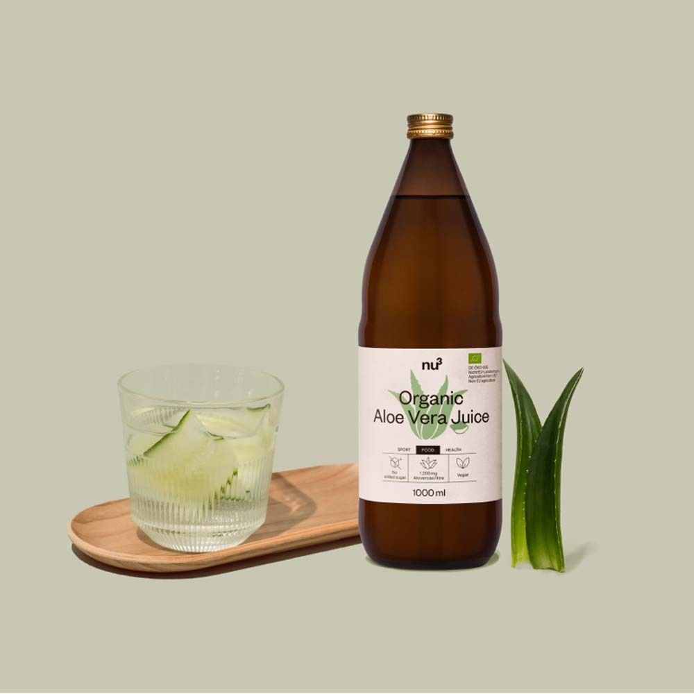 Une bouteille de jus d'aloe vera bio nu3, verre avec boisson, feuille d'aloe vera. Inscription : Organic Aloe Vera Juice.