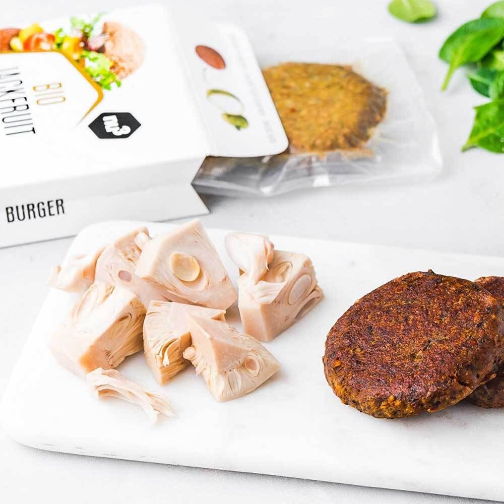Ingrédients pour burger sur une planche. Contient des morceaux de jacquier, des burgers et un emballage.