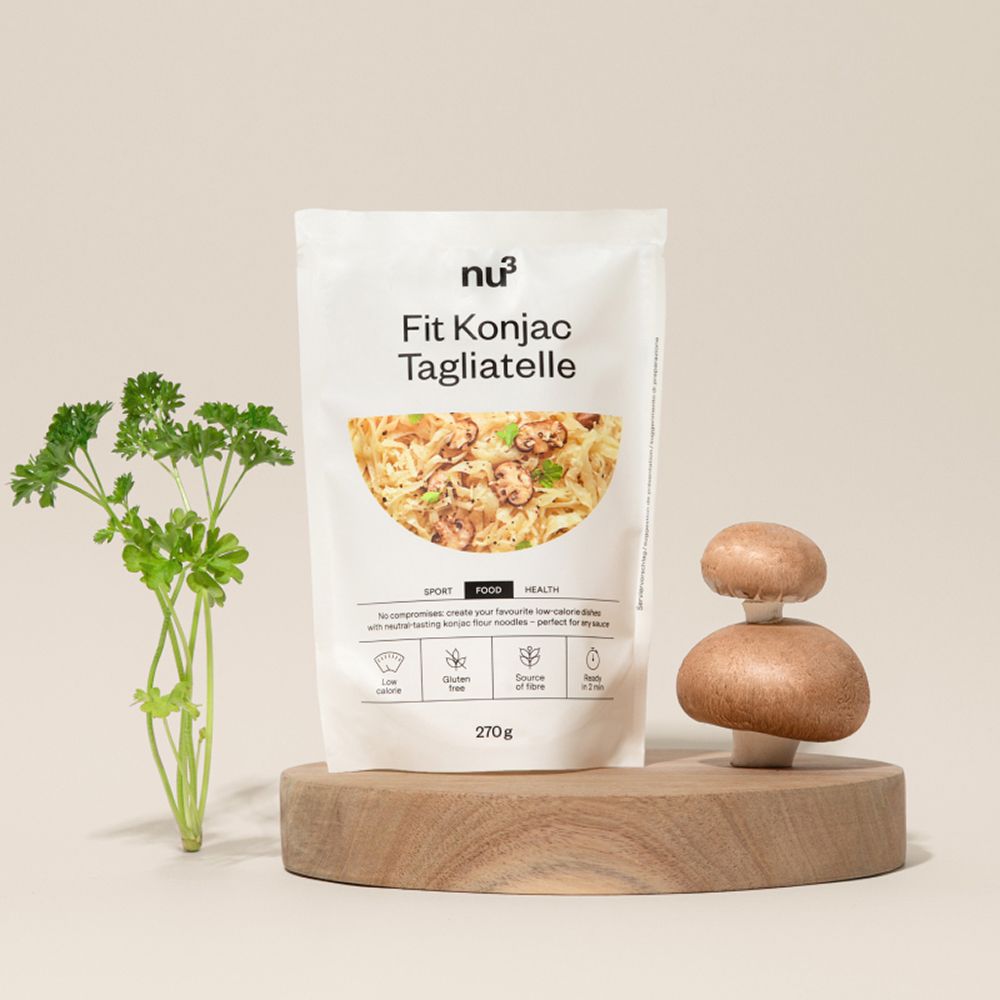 Un paquet de nu3 Fit Konjac Tagliatelle sur un socle en bois avec champignons et persil.